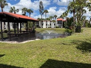 A gazebo sits on a grassy lawn near a pond with a water fountain — 3233 BENEVA ROAD UNIT 104, SARASOTA, FL