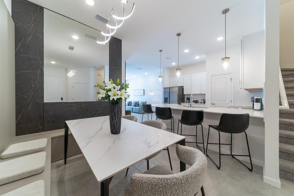 A dining area with a marble-topped table and bench seating sits beside a modern kitchen — 10364 EBB TIDE LANE, ORLANDO, FL
