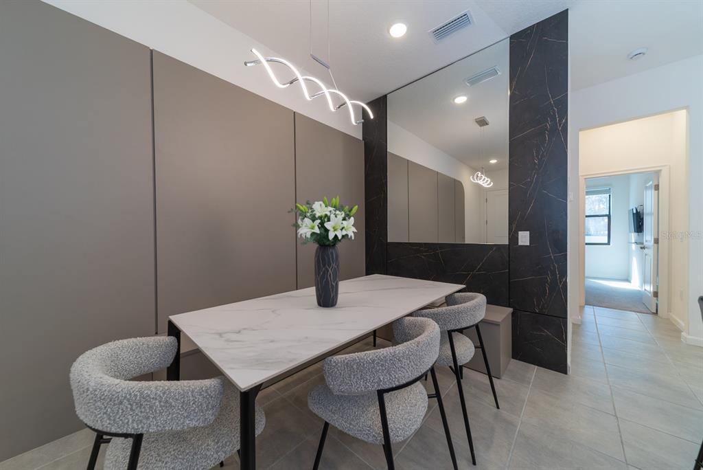 A dining area features a marble-topped table, textured chairs, a mirror, and a modern light fixture — 10364 EBB TIDE LANE, ORLANDO, FL