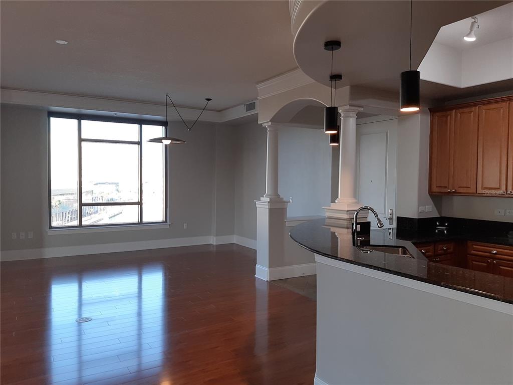 A kitchen with dark countertops and wood cabinets overlooks a living area with hardwood floors — 275 BAYSHORE BOULEVARD UNIT 904, TAMPA, FL