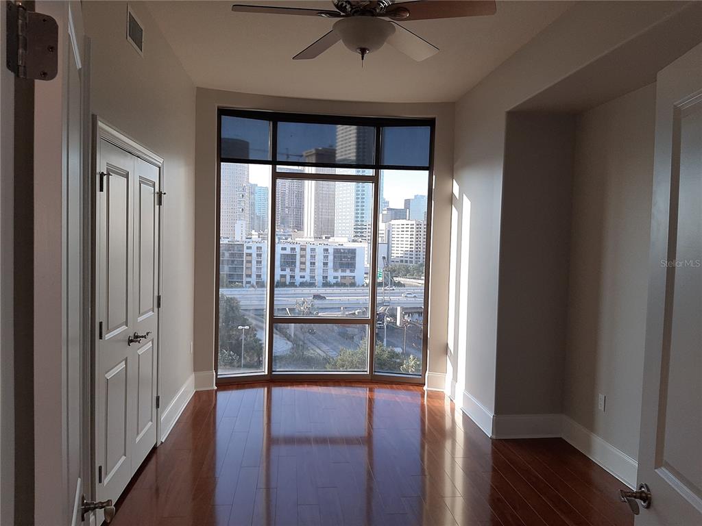 A room with hardwood floors, a ceiling fan, and large windows overlooking a city skyline — 275 BAYSHORE BOULEVARD UNIT 904, TAMPA, FL