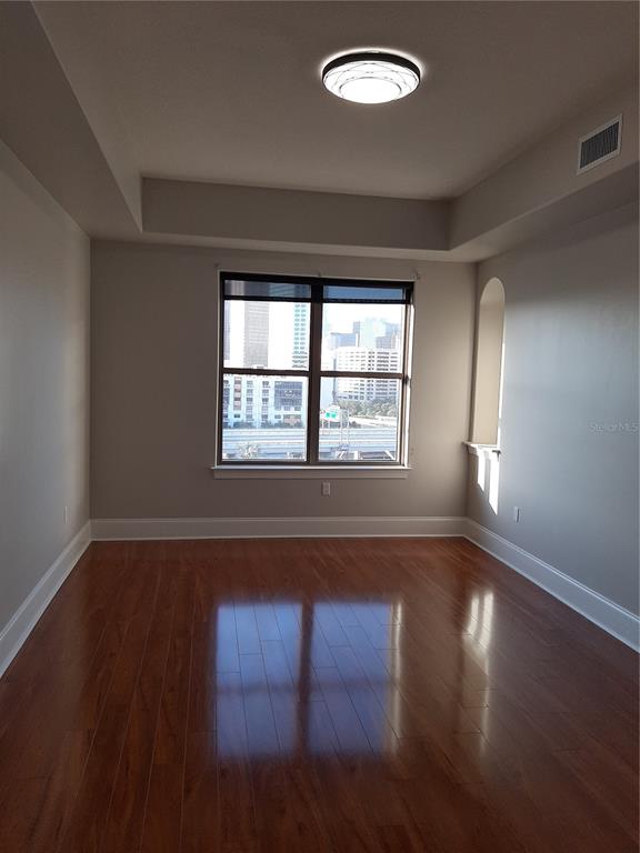An empty room with hardwood floors, a tray ceiling, and a window overlooking city buildings — 275 BAYSHORE BOULEVARD UNIT 904, TAMPA, FL