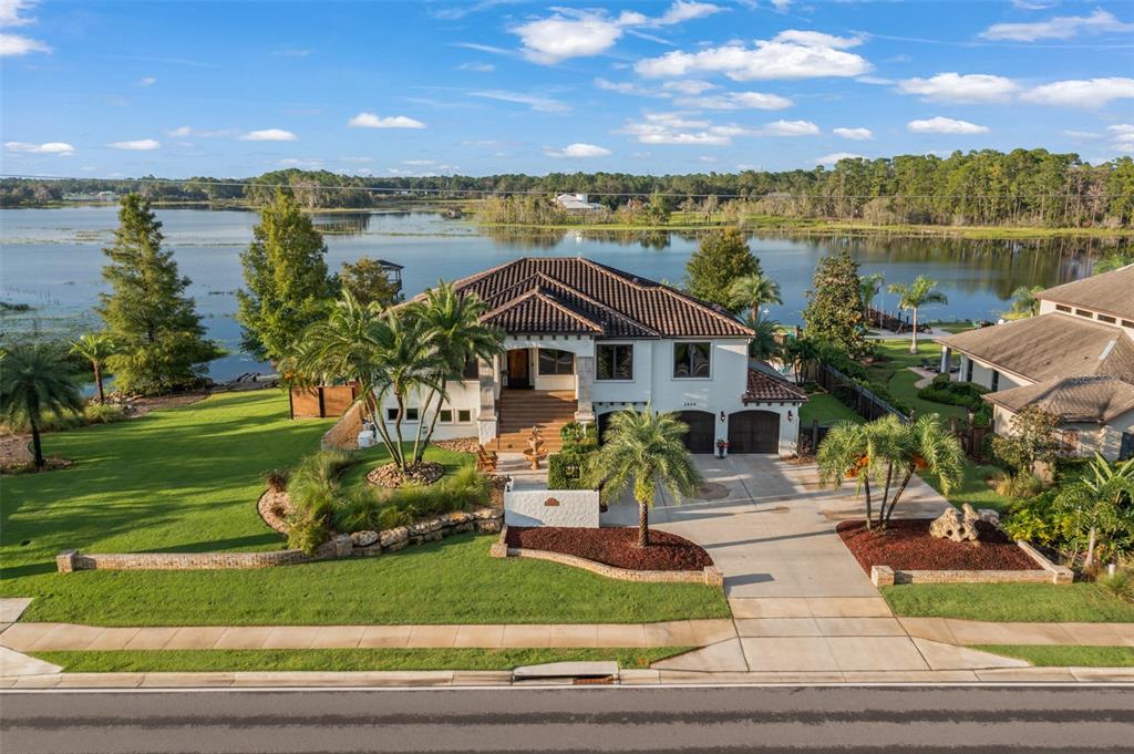 An aerial view of a two-story house with a tile roof situated on a lakefront lot — 2624 HOWLAND BOULEVARD, DELTONA, FL