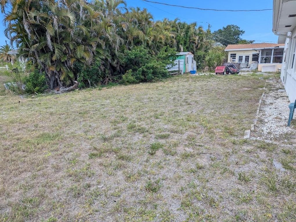 A grassy backyard features a small shed, palm trees, and a neighboring house — 175 ENGLEWOOD HEIGHTS ROAD, ENGLEWOOD, FL