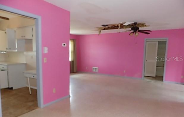 A living room with bright pink walls, beige carpet, and a damaged ceiling fan area — 175 ENGLEWOOD HEIGHTS ROAD, ENGLEWOOD, FL