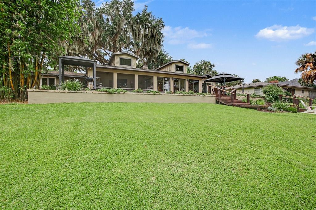 A tan house with a screened porch and a large grassy backyard under trees — 30139 JOHNSONS POINT ROAD, LEESBURG, FL