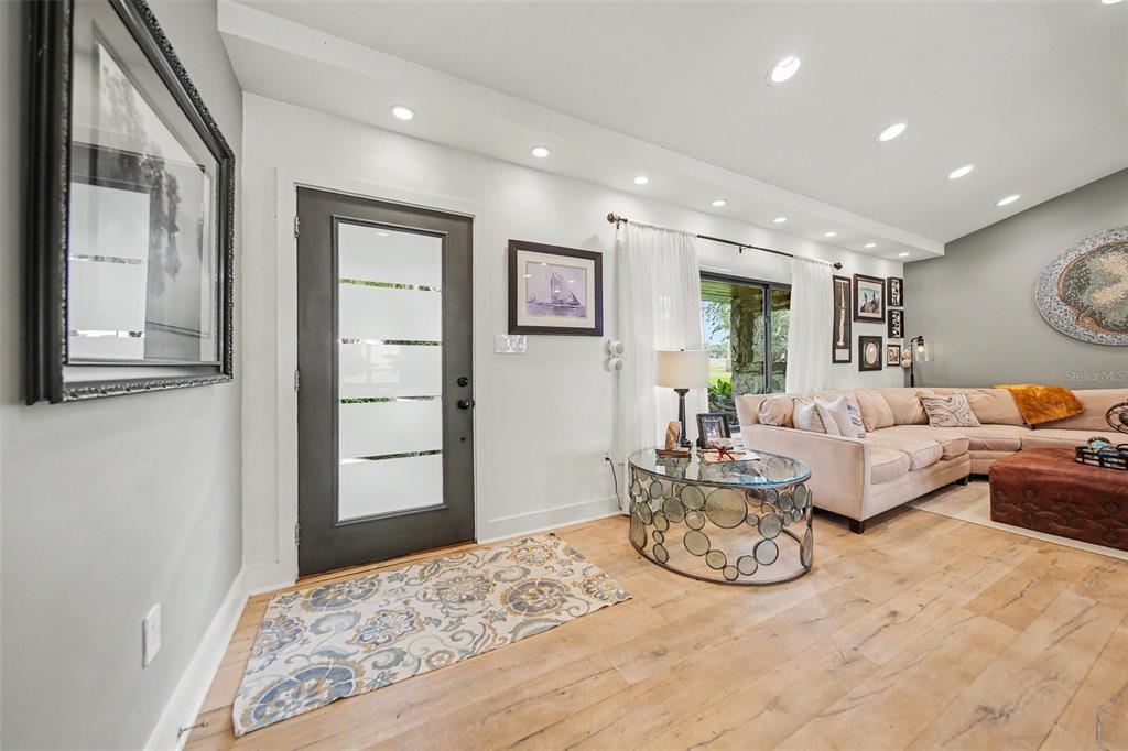 A living room features light wood flooring, a modern front door, and a sectional sofa — 30139 JOHNSONS POINT ROAD, LEESBURG, FL
