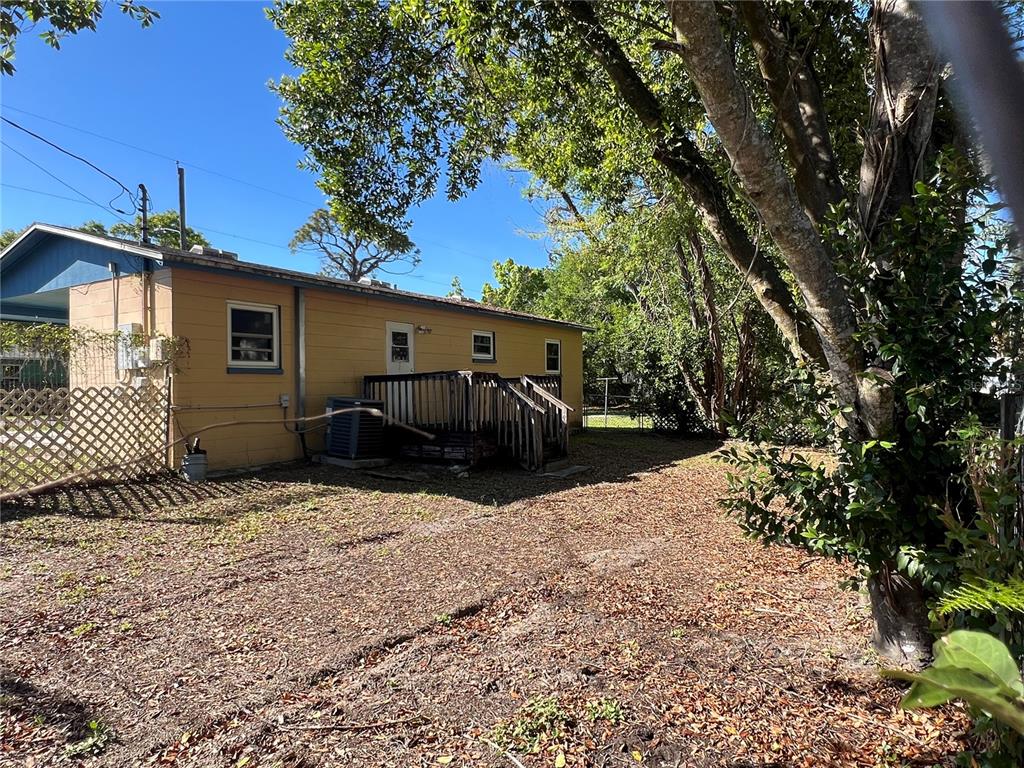 The exterior of a yellow house features a wooden deck and a lattice fence — 1602 E ANNONA AVENUE, TAMPA, FL