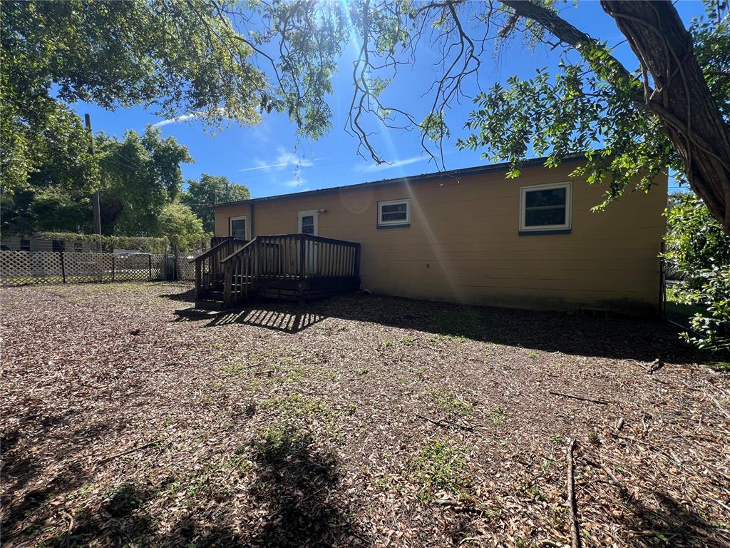 The exterior of a yellow house features a wooden deck and a fenced backyard — 1602 E ANNONA AVENUE, TAMPA, FL