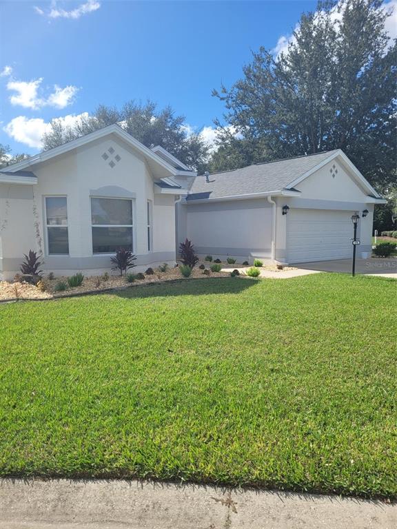 A single-story house with a beige exterior, a two-car garage, and a front lawn — 3194 KEARNS CORNER, THE VILLAGES, FL