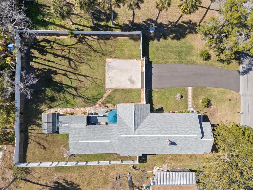 An aerial view shows a house with a gray roof, a fenced yard, and a driveway — 5150 LIMESTONE DRIVE, PORT RICHEY, FL