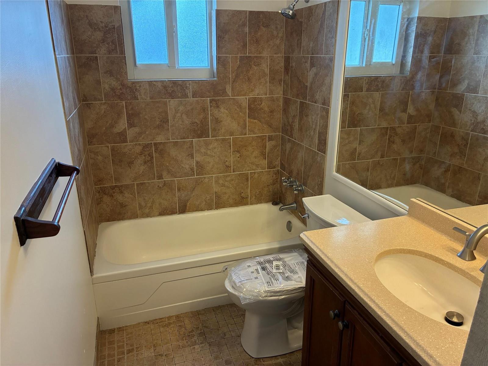 A bathroom features a tiled tub-shower combination, a toilet, and a vanity with a sink — 3021 E Golf Boulevard, Pompano Beach FL 33064, POMPANO BEACH, FL