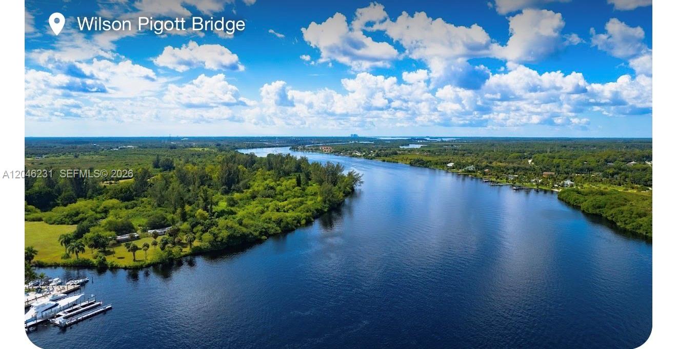 An aerial view shows a river flowing through a lush, green landscape under a cloudy sky — 705 LABRADOR AVE N, Lehigh Acres FL 33971, LEHIGH ACRES, FL