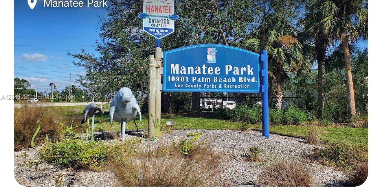 A blue sign for Manatee Park stands in a landscaped area with manatee sculptures — 705 LABRADOR AVE N, Lehigh Acres FL 33971, LEHIGH ACRES, FL