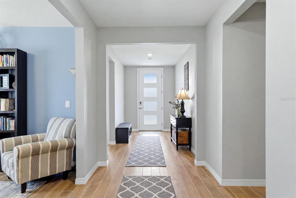 A bright entryway features light wood-look tile floors, a white front door, and a runner rug — 14026 GINNIE SPRINGS WAY, PARRISH, FL