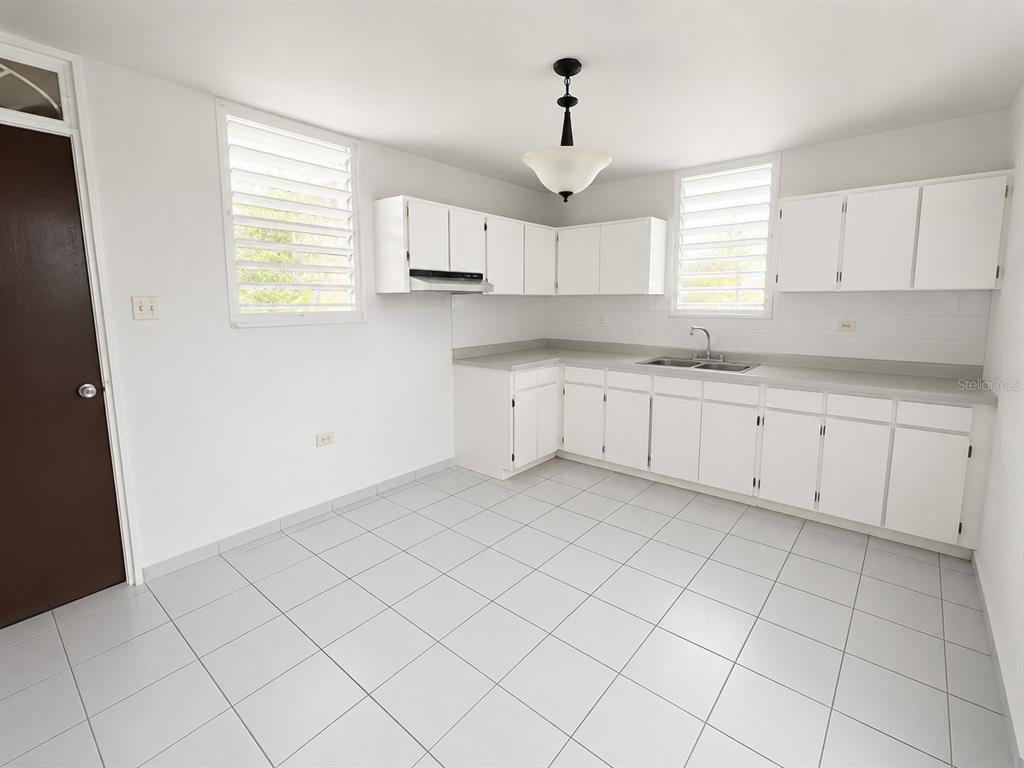 A kitchen with white cabinets, light countertops, and white tile flooring — H17 4TH STREET, ARROYO, PR