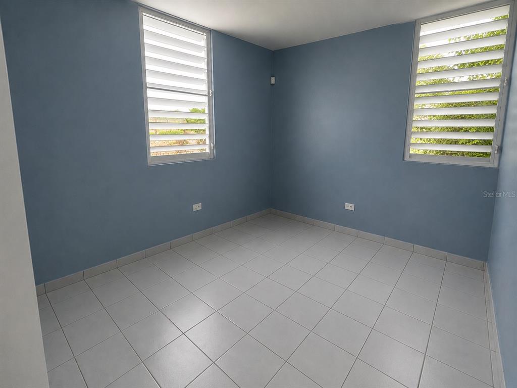 An empty room with blue walls, white tile flooring, and two louvered windows — H17 4TH STREET, ARROYO, PR
