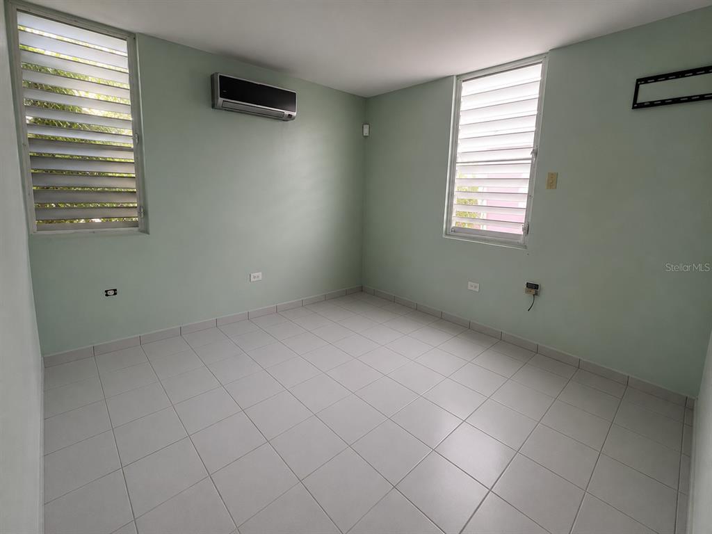 An empty room with light green walls, white tile flooring, and two louvered windows — H17 4TH STREET, ARROYO, PR