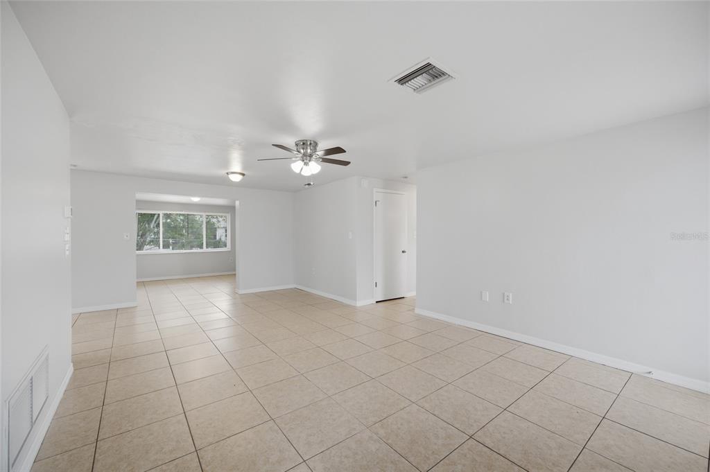 An open-concept living area features light-colored tile flooring, white walls, and a ceiling fan — 3029 HUNTINGTON ROAD, HOLIDAY, FL