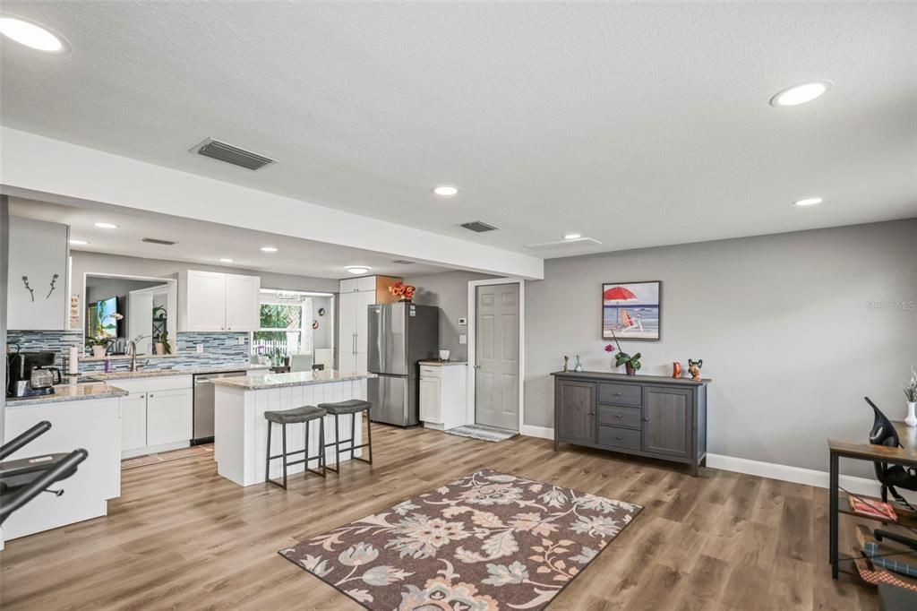 A kitchen with white cabinetry and an island opens into a living area with flooring — 4704 KOALA DRIVE, HOLIDAY, FL