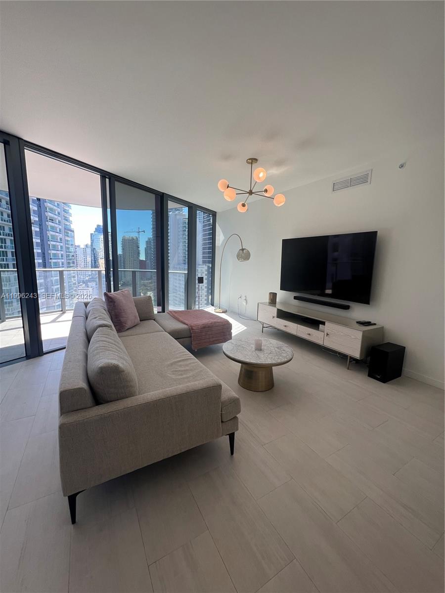 A modern living room features a sectional sofa, marble coffee table, and floor-to-ceiling windows — 1000 Brickell Plaza # 2701, Miami FL 33131, MIAMI, FL