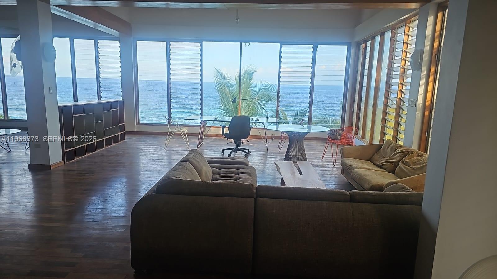 A living room with a large sectional sofa, a desk, and floor-to-ceiling windows overlooking the ocean — 00 Oracabessa, St. Mary, NA, NA