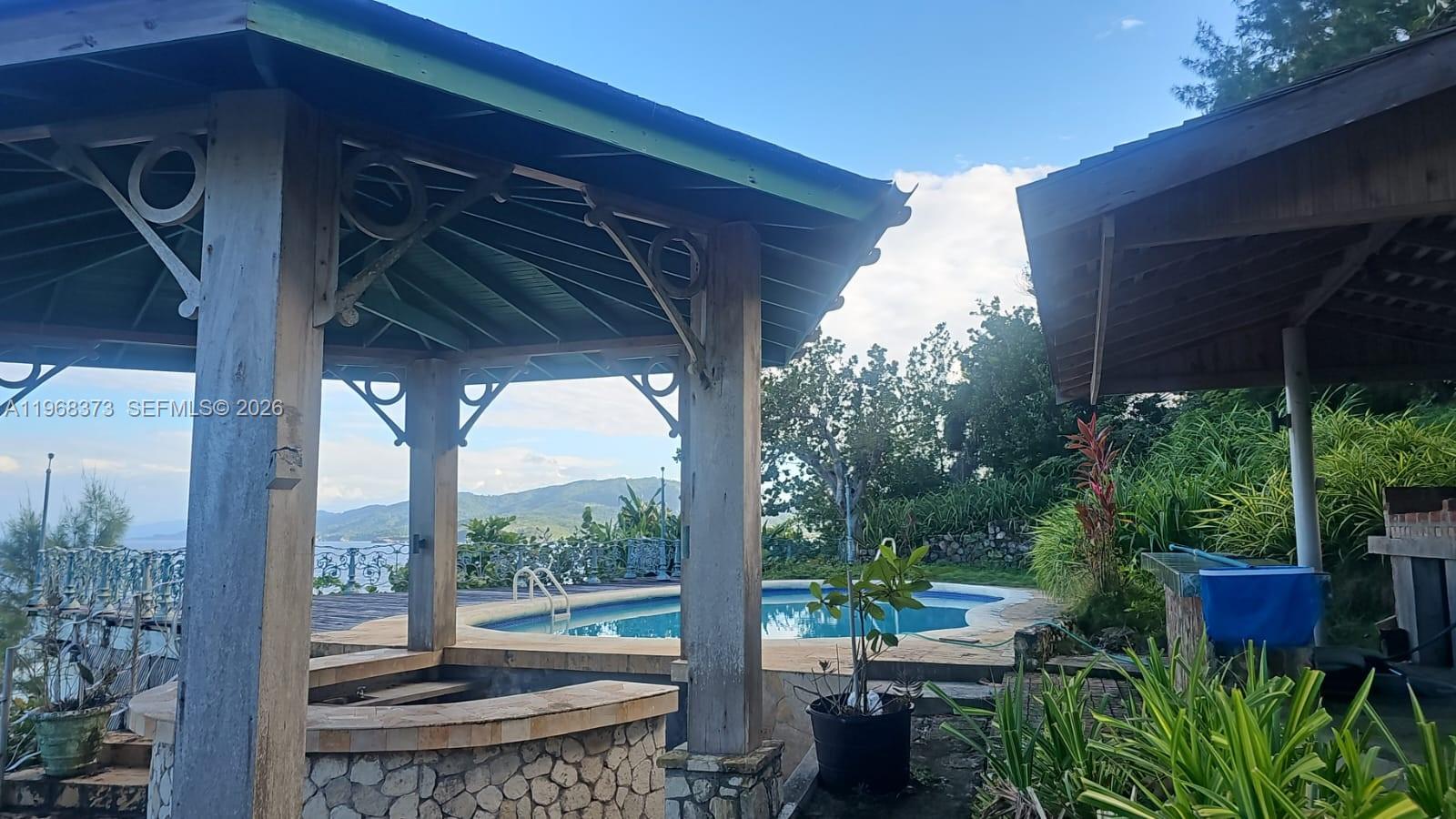 An outdoor patio area features two wooden gazebos, a swimming pool, and mountain views — 00 Oracabessa, St. Mary, NA, NA