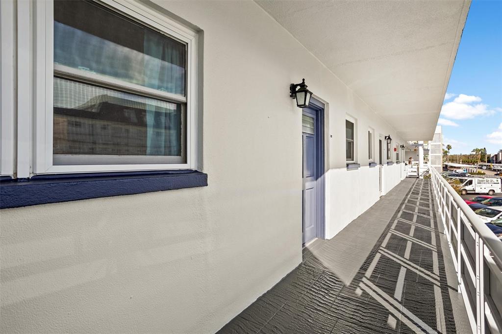 An exterior walkway with a blue door and window along a white building — 5955 30TH AVENUE S UNIT 202, GULFPORT, FL