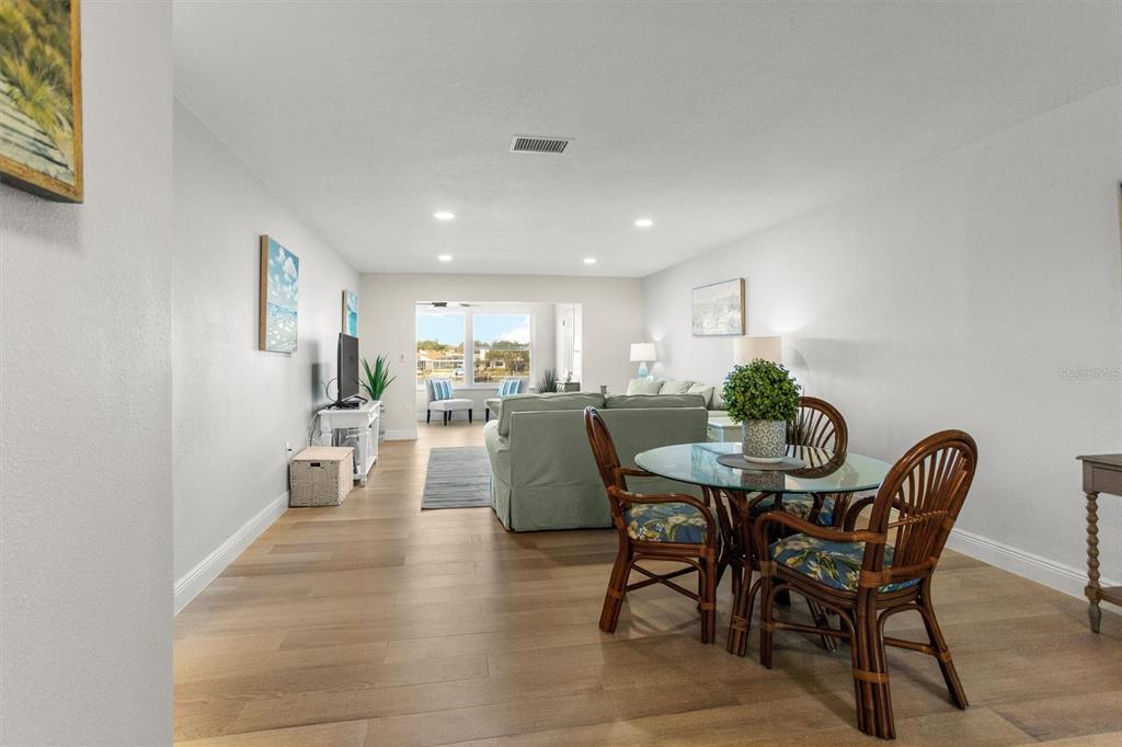 A living and dining area features light wood flooring, a glass-top table, and patio views — 5955 30TH AVENUE S UNIT 202, GULFPORT, FL