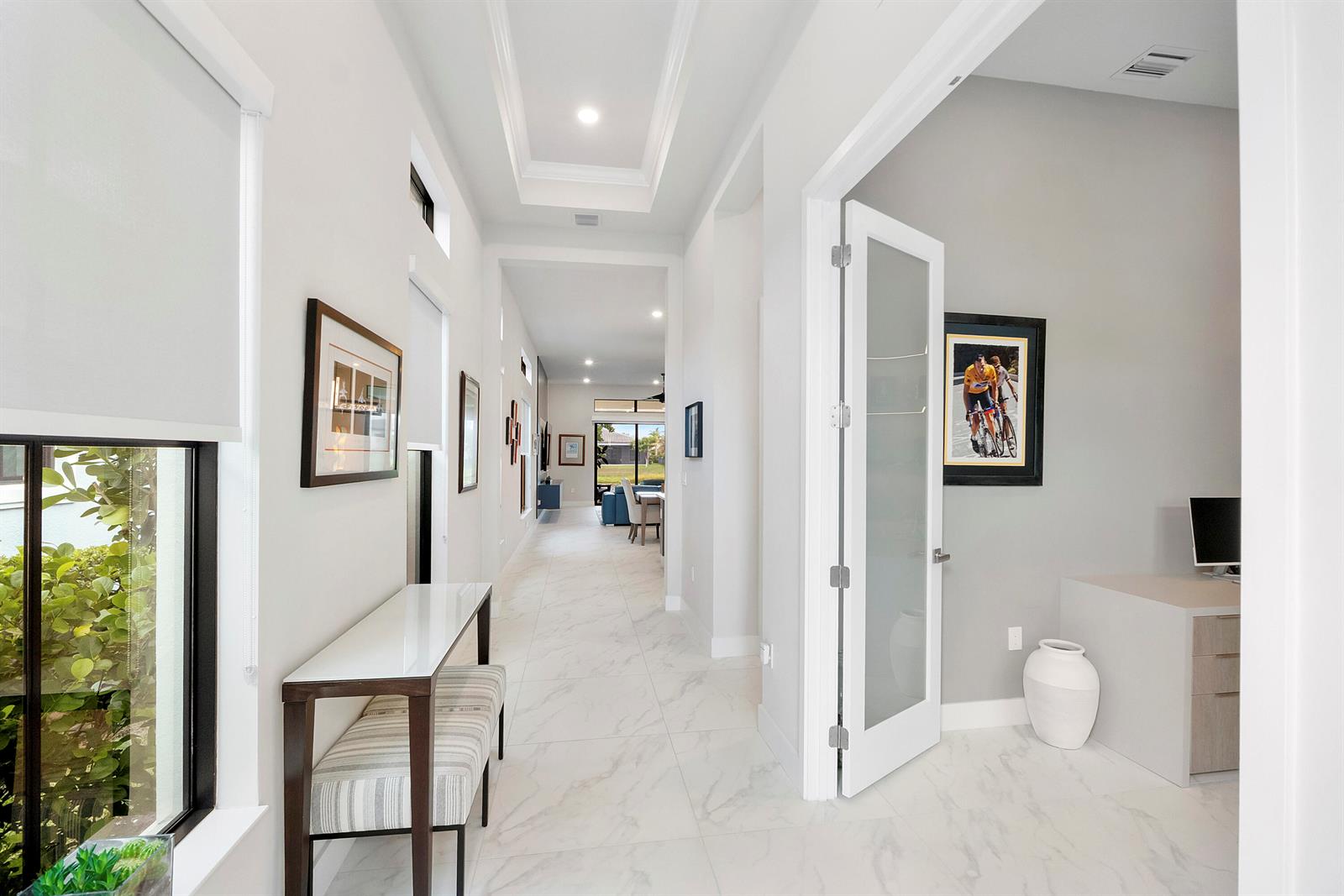A bright hallway with marble-look tile flooring leads toward a living area with glass doors — 7885 Ironwood Way, Parkland FL 33067, PARKLAND, FL