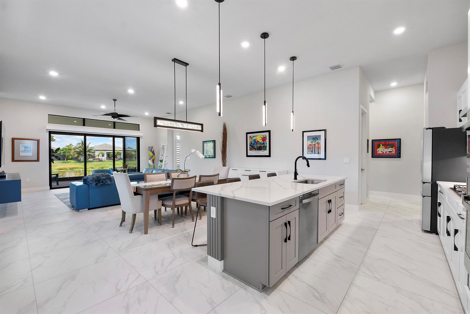 An open-concept kitchen and dining area features a gray island, white countertops, and tile flooring — 7885 Ironwood Way, Parkland FL 33067, PARKLAND, FL