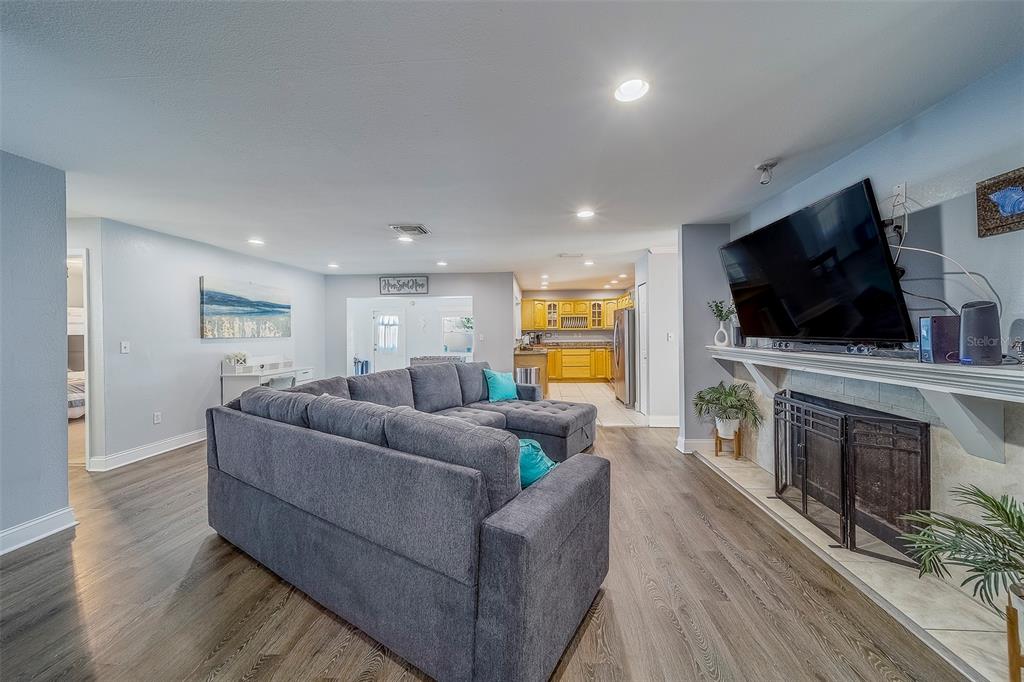 A living room features a gray sectional sofa, a fireplace with a mounted television, and flooring — 14414 91ST AVENUE, SEMINOLE, FL