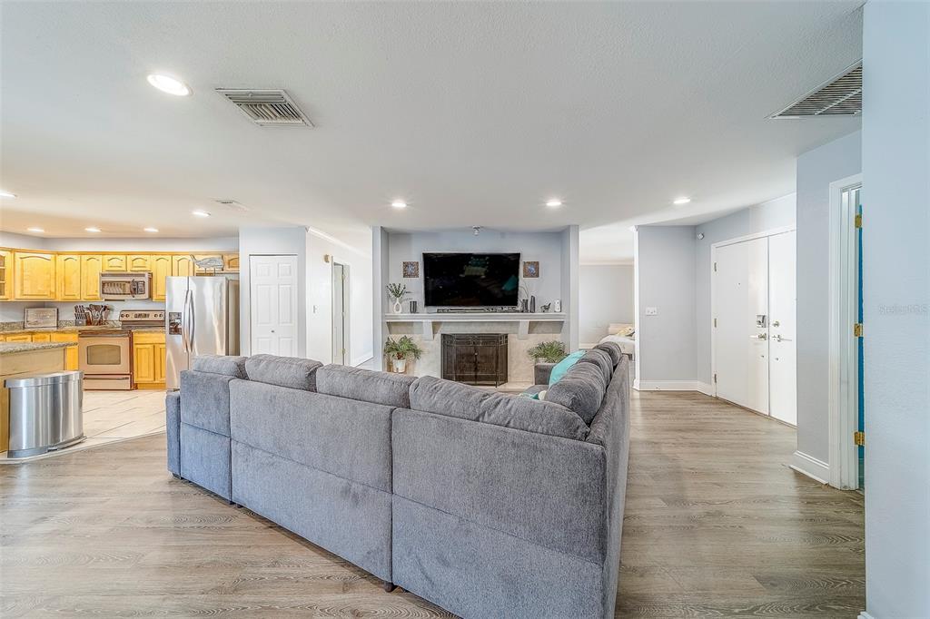 A living room with a gray sectional sofa faces a fireplace and wall-mounted television — 14414 91ST AVENUE, SEMINOLE, FL