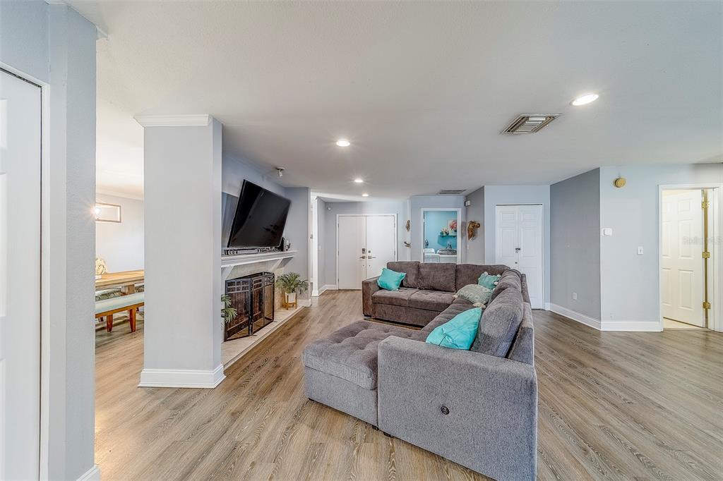 A living room features a gray sectional sofa, a fireplace with a television, and wood-look flooring — 14414 91ST AVENUE, SEMINOLE, FL