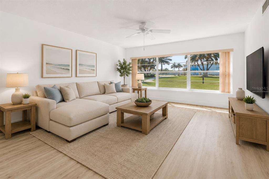 A living room features a beige sectional sofa, a wooden coffee table, and large windows — 300 64TH AVENUE UNIT 117, ST PETE BEACH, FL