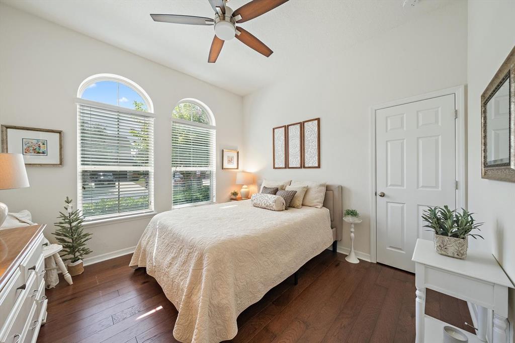 A bedroom features hardwood floors, a ceiling fan, two arched windows, and a queen bed — 12940 BLISS LOOP, BRADENTON, FL