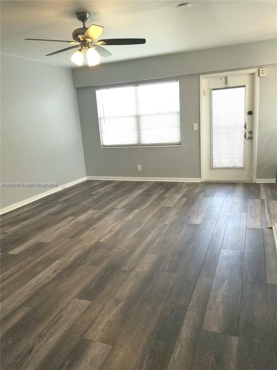 A living room features gray walls, wood-look flooring, a ceiling fan, and a glass-paneled door — 285 Fanshaw G # G, Boca Raton FL 33434, BOCA RATON, FL