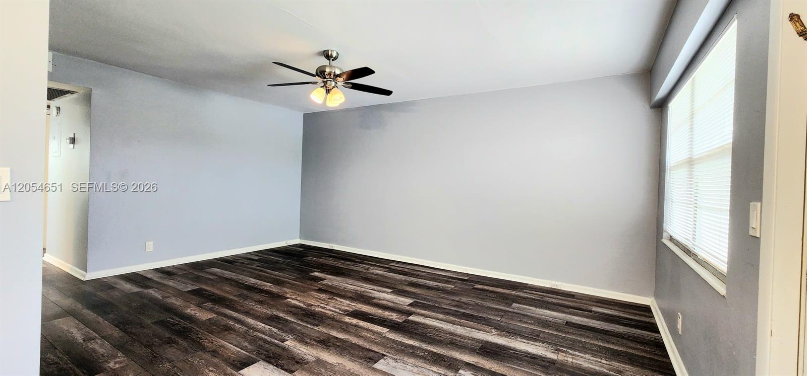 An empty room features light gray walls, dark wood-look flooring, and a ceiling fan — 285 Fanshaw G # G, Boca Raton FL 33434, BOCA RATON, FL