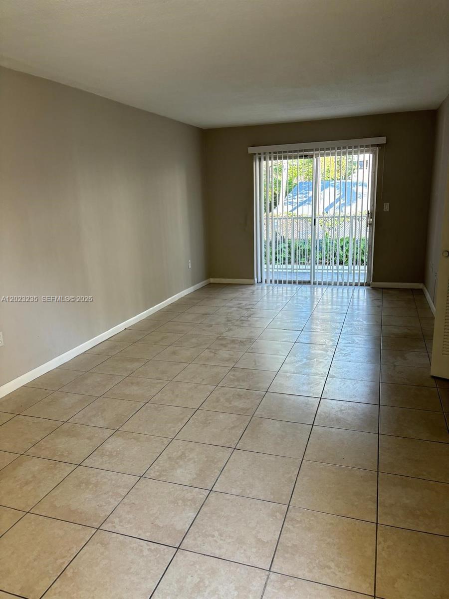 An empty room features beige walls, light-colored tile flooring, and a sliding glass door — 3050 S Dixie Hwy # 203, Miami FL 33133, MIAMI, FL