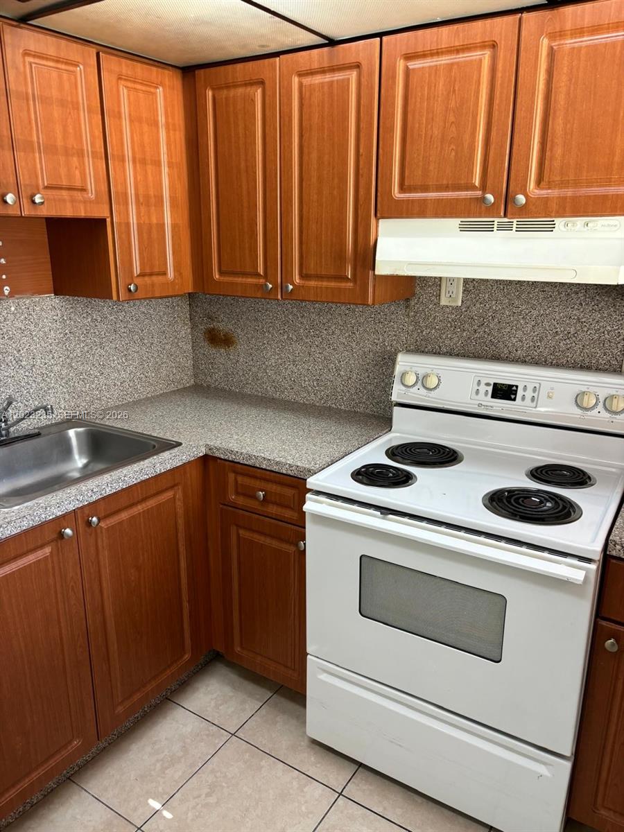 A kitchen features wood cabinets, a white electric stove, and a speckled laminate countertop — 3050 S Dixie Hwy # 203, Miami FL 33133, MIAMI, FL