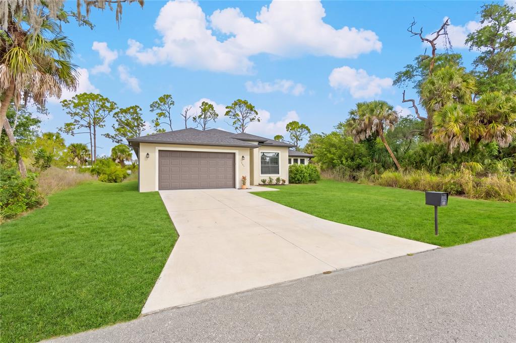 A single-story house with a two-car garage and a concrete driveway sits on a lawn — 241 HOFFER STREET, PORT CHARLOTTE, FL