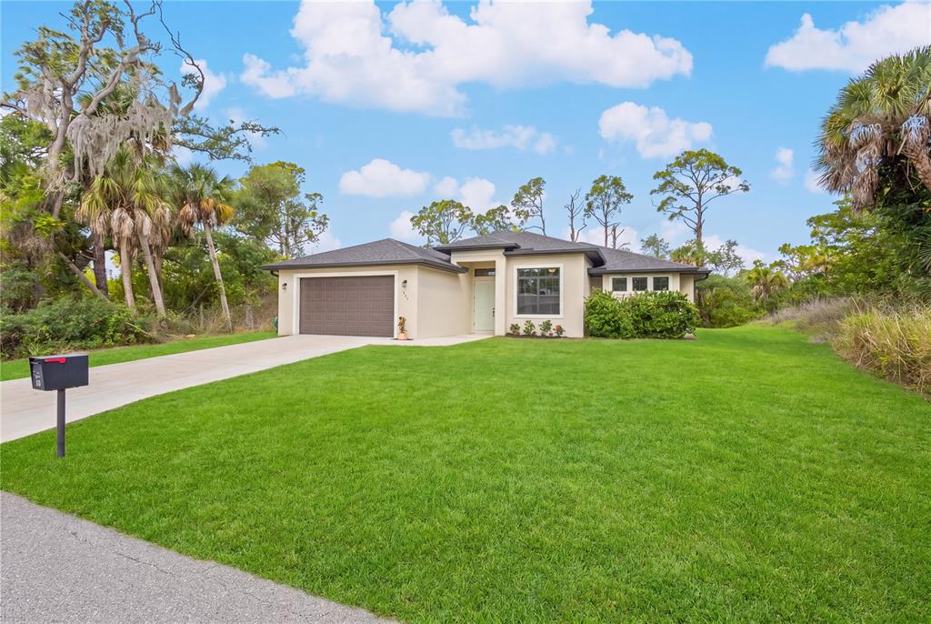 A single-story house with a beige exterior, a two-car garage, and a green lawn — 241 HOFFER STREET, PORT CHARLOTTE, FL