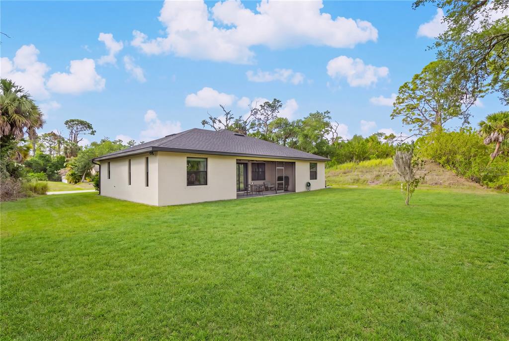 The exterior of a beige house with a screened-in patio sits on a large lawn — 241 HOFFER STREET, PORT CHARLOTTE, FL