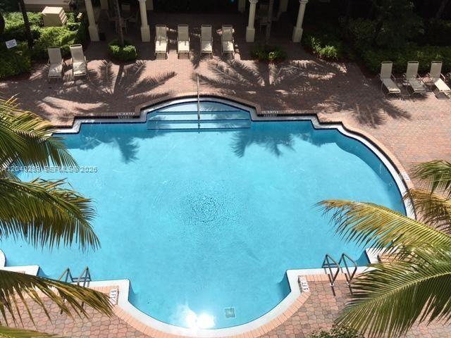 An aerial view shows a swimming pool surrounded by a brick deck and lounge chairs — 2409 Renaissance Way # 409, Boynton Beach FL 33426, BOYNTON BEACH, FL