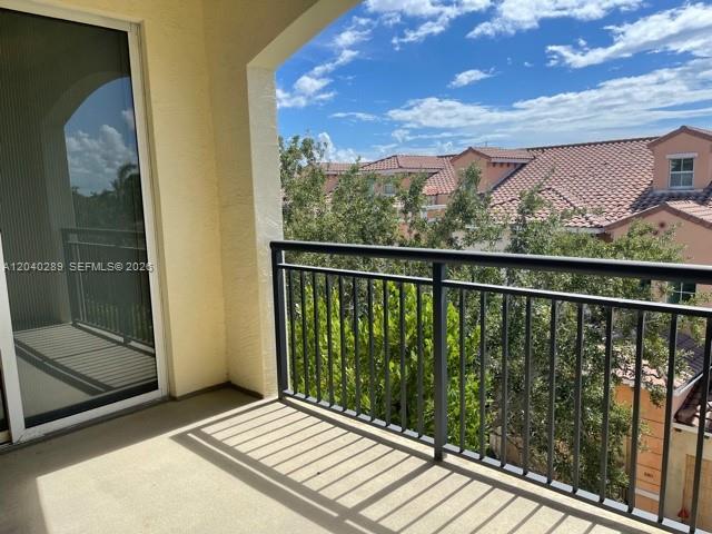 A balcony with a black metal railing overlooks trees and neighboring residential buildings — 2409 Renaissance Way # 409, Boynton Beach FL 33426, BOYNTON BEACH, FL