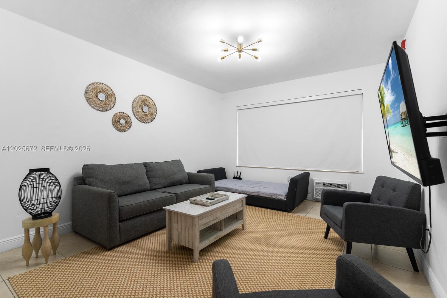 A living room features a gray sofa, two armchairs, a coffee table, and wall decor — 301 86th St # 1, Miami Beach FL 33141, MIAMI BEACH, FL