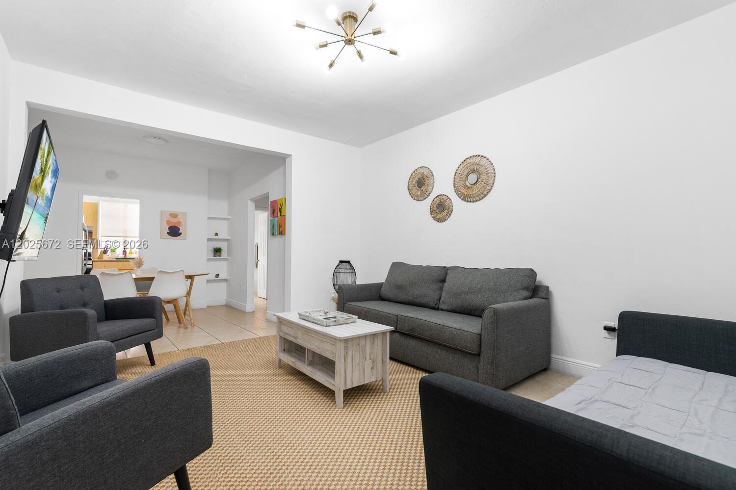 A living room features gray furniture, a light wood coffee table, and a beige rug — 301 86th St # 1, Miami Beach FL 33141, MIAMI BEACH, FL