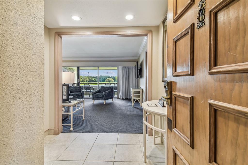 A tiled entryway opens into a carpeted living area with a view of a golf course — 36750 US HIGHWAY 19 N UNIT 04308, PALM HARBOR, FL