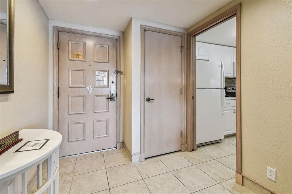 A tiled entryway features a front door, a closet door, and a view into a kitchen — 36750 US HIGHWAY 19 N UNIT 04308, PALM HARBOR, FL