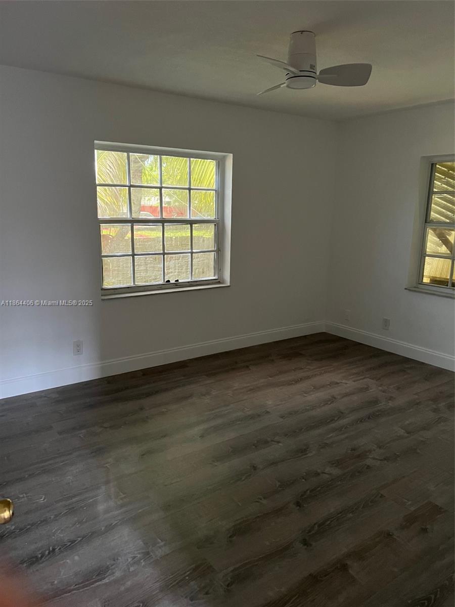 An empty bedroom features white walls, dark wood-look flooring, a ceiling fan, and two windows — 802 S 24th Ave, Hollywood FL 33020, HOLLYWOOD, FL